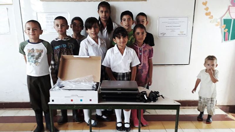 Children in school in Colombia standing in front of computers donated by Trelleborg