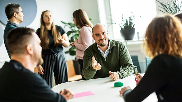 Colleagues having a discussion in a bright, modern office, highlighting teamwork and a welcoming work culture.