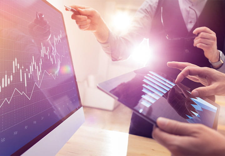 Two colleagues looking at shares using tablet and laptop