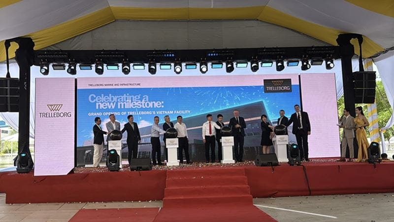 Grand opening ceremony of Trelleborg’s new Vietnam facility under a white and yellow tent. A red-carpeted stage features two large LED screens displaying the Trelleborg logo and event details.