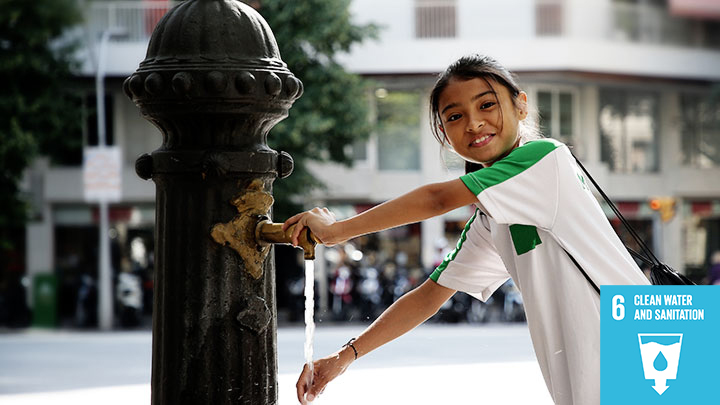 Happy girl using public water pipe outside in city