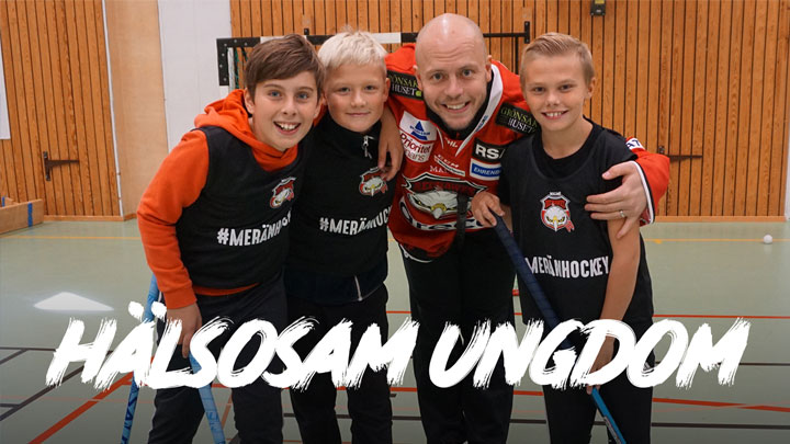 Three children and man from ice hockey team Malmö Redhawks in school's sports hall