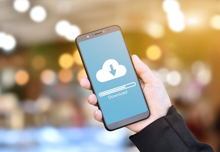 Hand holding a smartphone with a cloud download icon and progress bar on the screen