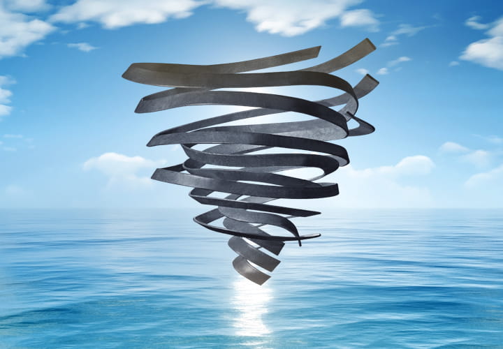 Rubber-shaped tornado above a calm ocean under a bright blue sky