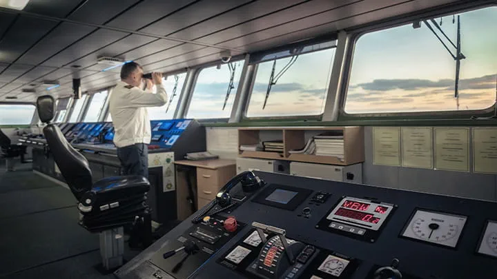 Captain-on-ship-bridge-monitoring-navigation-screens