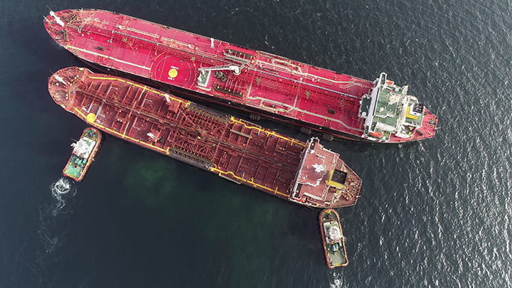ship to ship operation at offshore area. Top view of two crude oil tankers with two tug boats