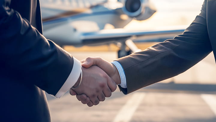 Deux personnes se serrant la main dans un aéroport avec un avion en arrière-plan.