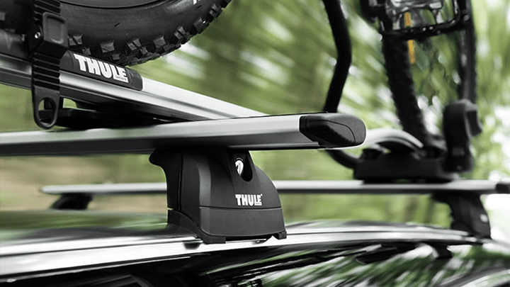 Système de porte-vélos de marque Thule monté sur le toit d'un véhicule, avec un vélo fixé sur le dessus du véhicule