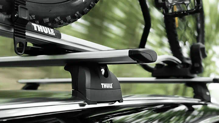 Un portabicicletas de la marca Thule montado en el techo con una bicicleta fijada en la parte superior de un vehículo