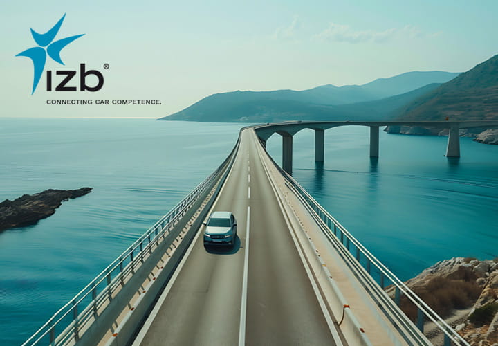 IZB exhibition banner featuring a car driving across a bridge over blue water, with the IZB logo and mountain scenery in the background