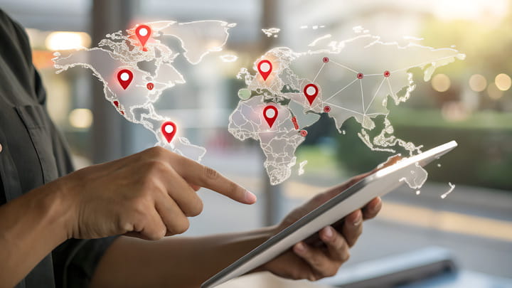 Person using a tablet with a digital world map and location pins, representing local presence, global capabilities, and an international network.