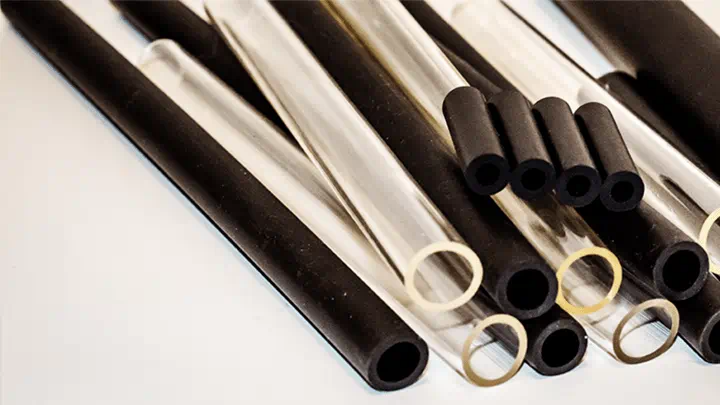 Collection of black and transparent rubber hoses arranged on a white surface
