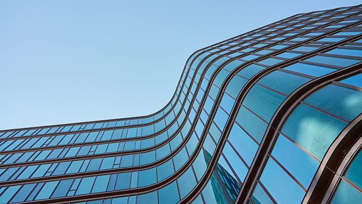 Moderne Glasfassade mit geschwungenem architektonischem Design unter strahlend blauem Himmel