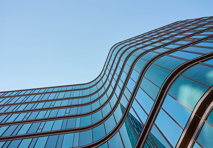 Modern glass facade with curved architectural design under clear blue sky