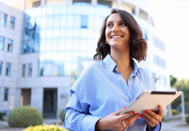 Professional holding a tablet outside a modern glass office building