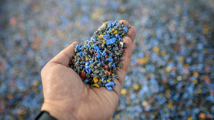 Hand holding recycled plastic granules, representing circular materials and sustainable production for circular sealing profiles