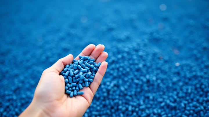 Main tenant des granulés de PVC bleu utilisés pour l'extrusion de profilés