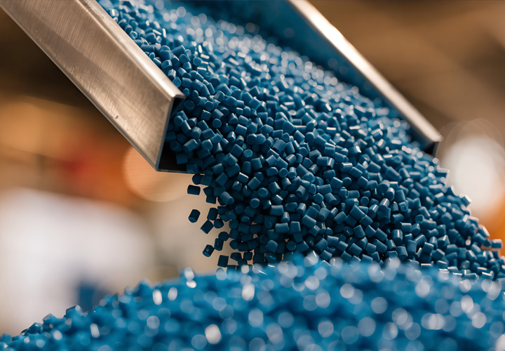 Engineered polymer pellets in a production process, highlighting material expertise, quality control, and precision manufacturing