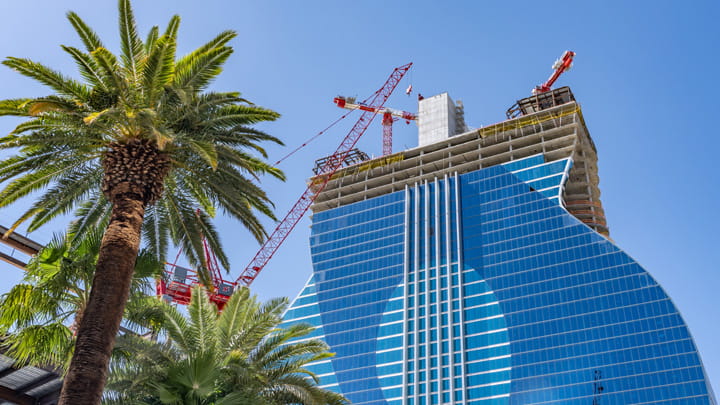 Hard Rock Hotel & Casino under construction in Las Vegas with a guitar-shaped glass facade and tower cranes