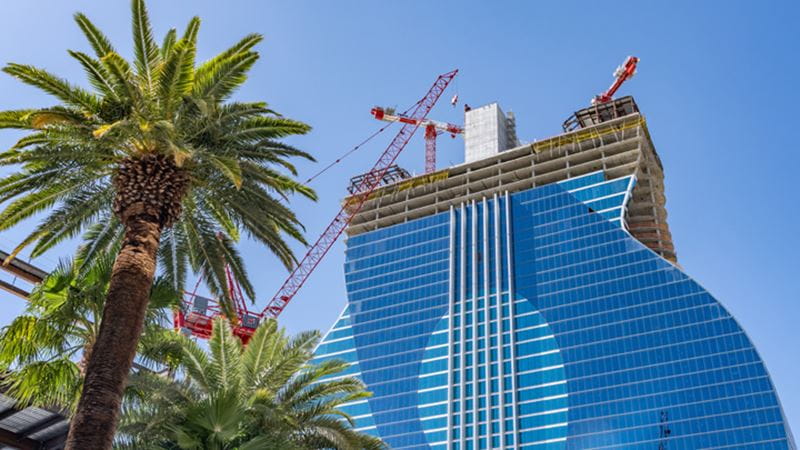 Hard Rock Hotel & Casino en construction à Las Vegas avec une façade vitrée en forme de guitare et des grues.