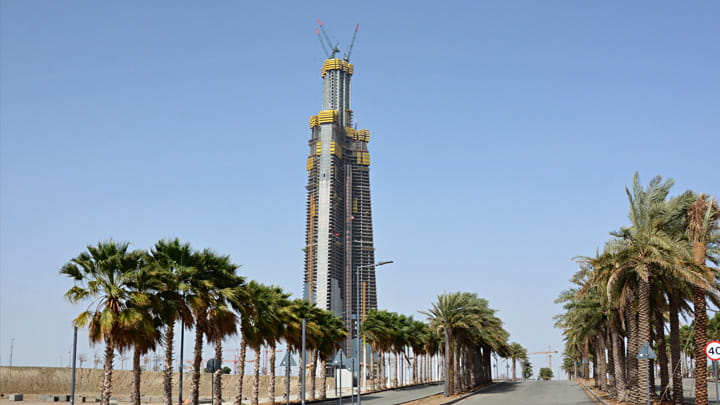 Jeddah Tower construction site in Saudi Arabia with supertall skyscraper and palm‑lined access road.