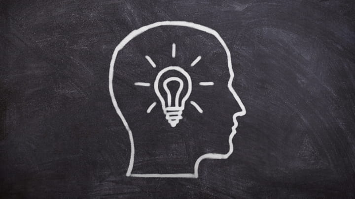 Head with a light bulb drawn on a blackboard