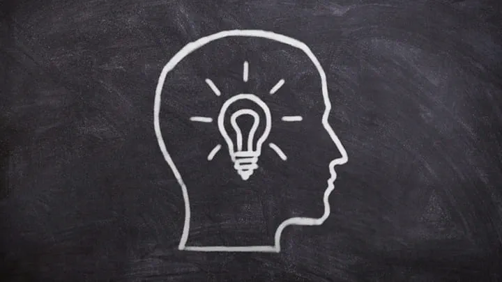Head with a light bulb drawn on a blackboard