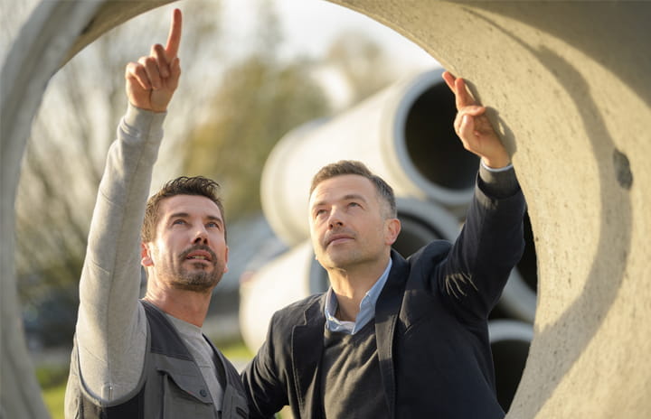 Two men looking at a concrete pipe