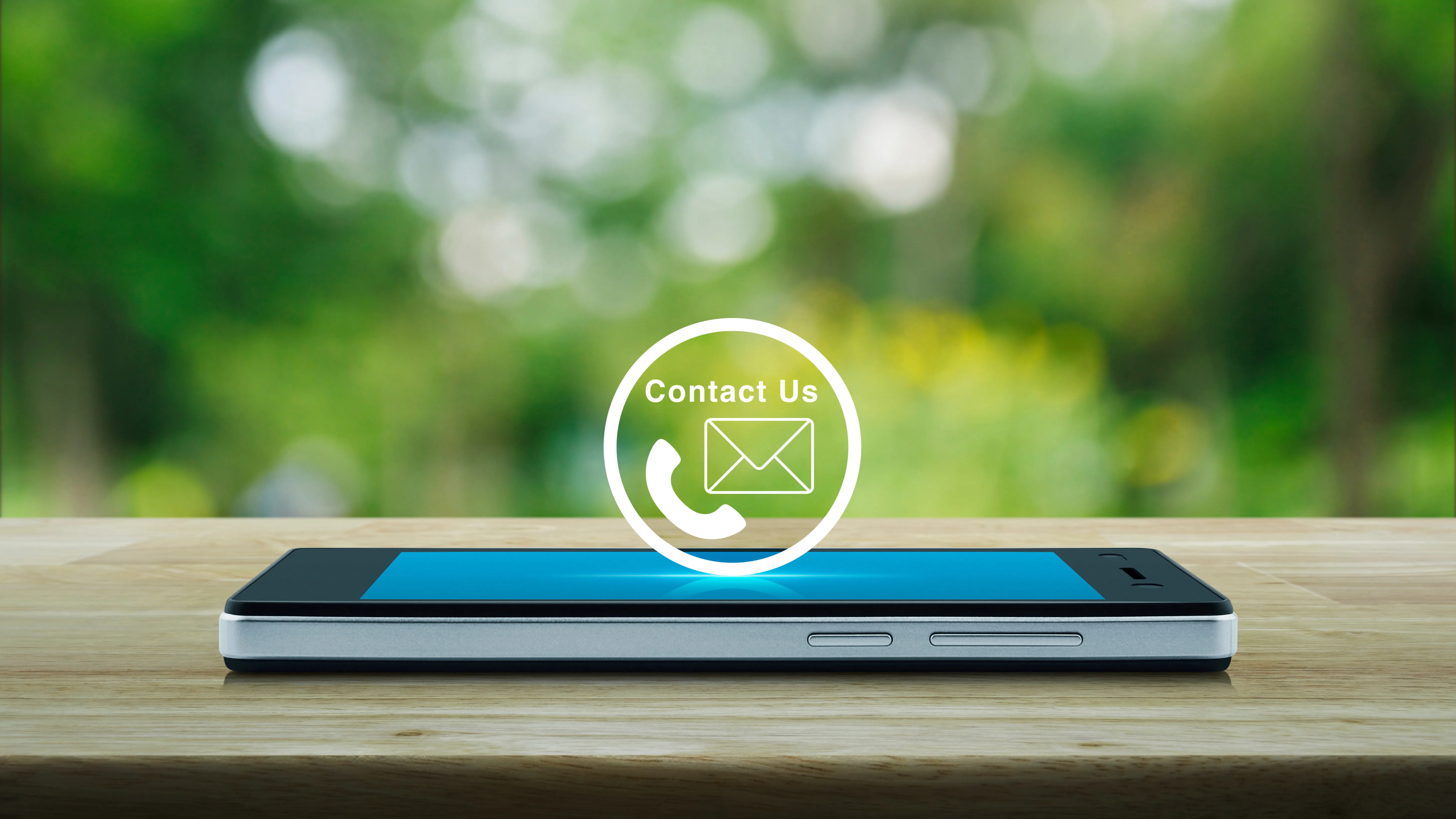 Smartphone sur une surface en bois avec icônes de contact pour le téléphone et l'e-mail