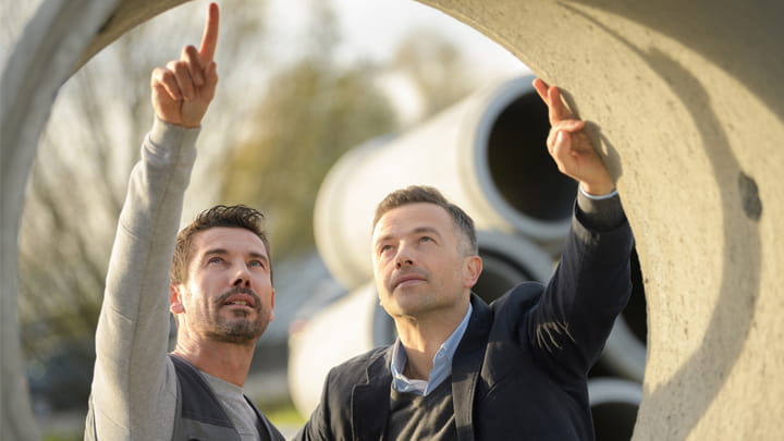 Two men looking at a concrete pipe