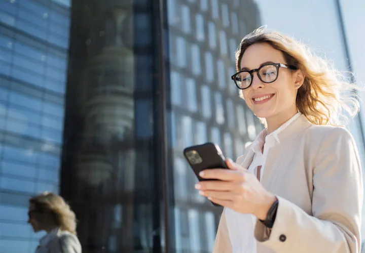 Personne utilisant un smartphone devant un bâtiment moderne en verre