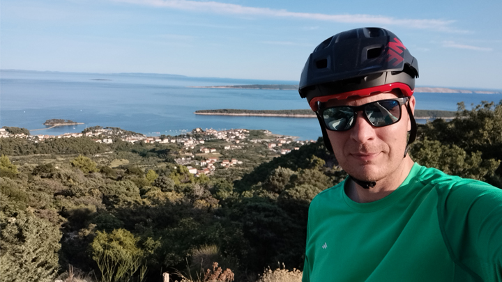 Rok Šilc wearing a biking helmet and glasses, with the sea in the background