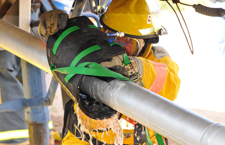 A man wearing protective equipment fixing a pipe that conveys hazardous materials