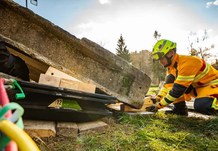 Rescue worker in safety gear securing concrete slabs outdoors during a training or emergency response