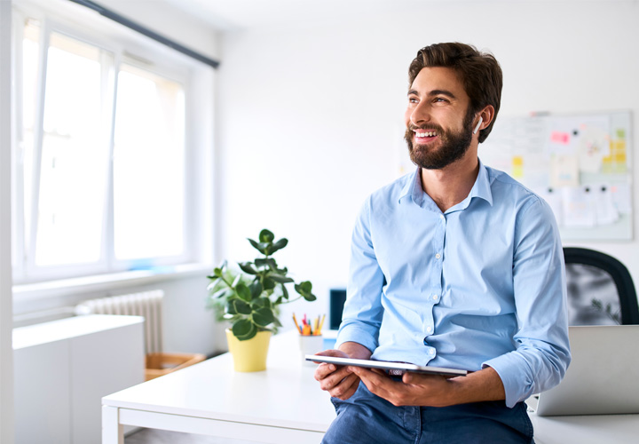 About us Smiling businessman with headphones using a digital tablet in his office